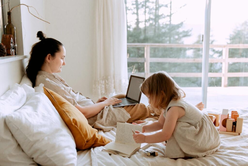 Momtrepreneur Mother working remotely while daughter drawing nearby